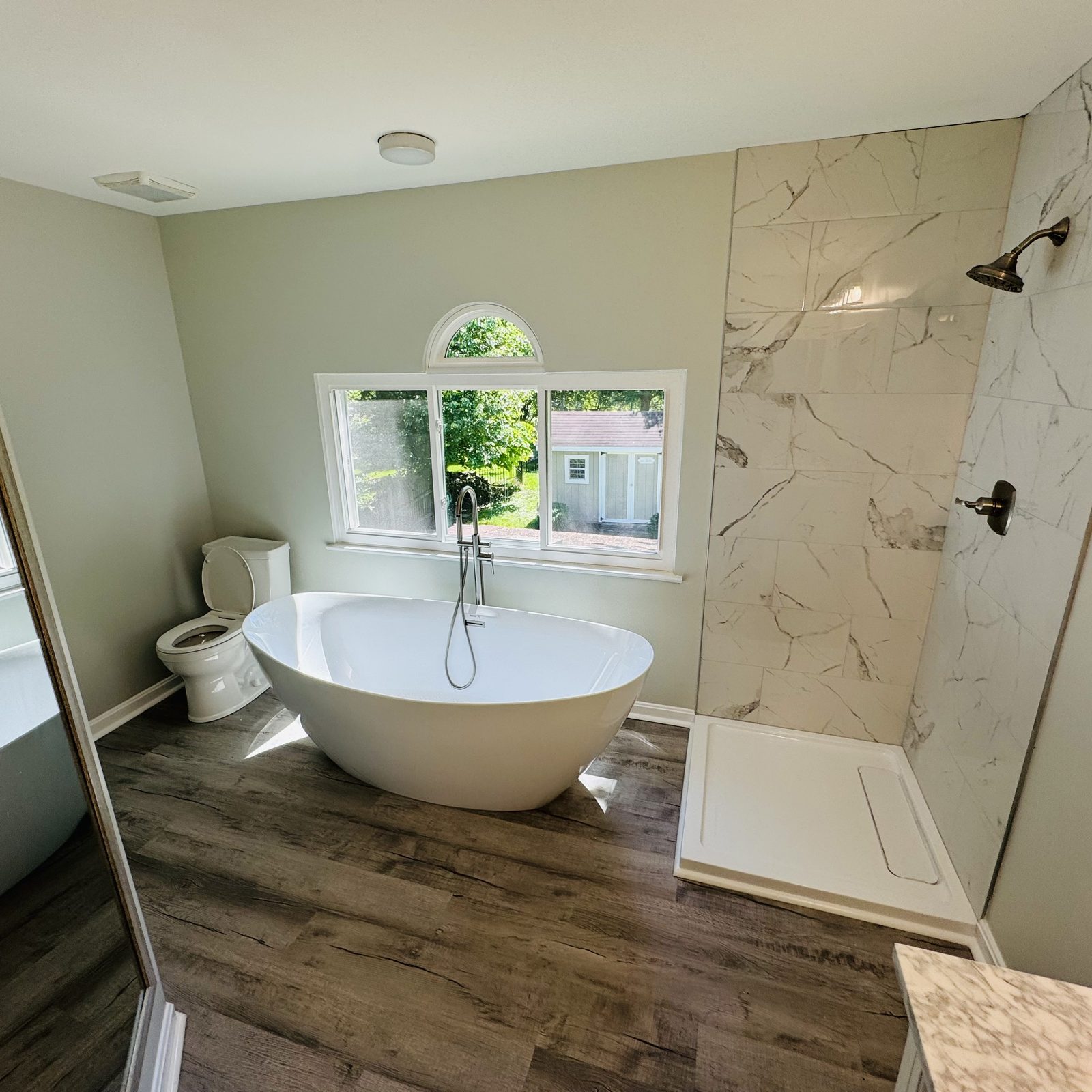 Freestanding tub with marble surround in a renovated bathroom